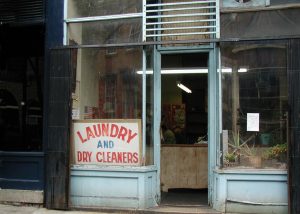 Display window with a sign saying Laundry and Dry Cleaners and a few plants - copyright Romy Ashby