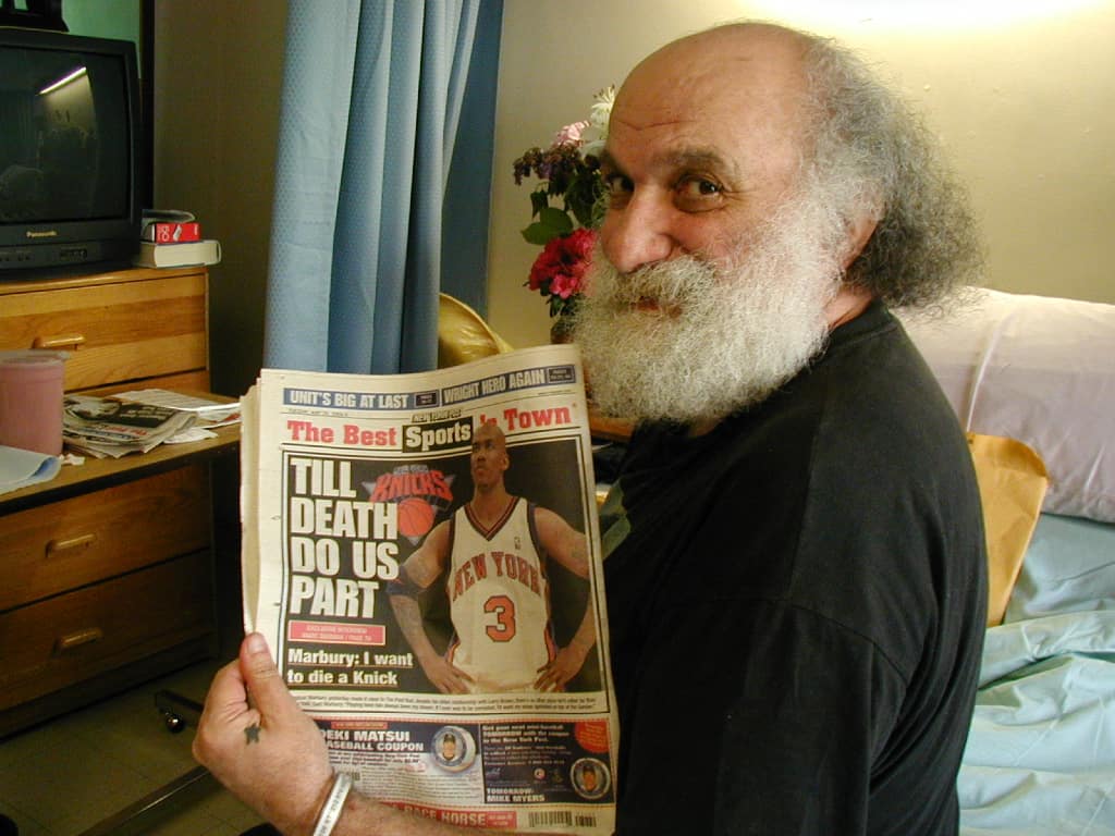 Ira Cohen holding up a newspaper with the headline "TILL DEATH DO US PART" - copyright Romy Ashby